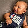 baby, infant, child, smiling, happy, portrait, indoor, sitting, couch, gray_background, basketball, nba, jersey, sportswear, close_up, face, eyes, mouth, hands, casual