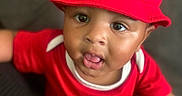 Zyair joined the competition — help win amazing prizes! baby, child, infant, portrait, red_hat, red_outfit, sitting, face, eyes, tongue_out, curious, indoor, couch, close_up, fashion, sportswear, jordan_logo, smiling, photography, adorable