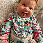 Lilith joined the competition — help win amazing prizes! baby, child, infant, smiling, happy, portrait, close_up, indoors, seated, onesie, colorful_clothing, hearts, strawberries, cookies, donut_pattern, baby_seat, cushion, playful, cozy, face