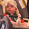 Lilith joined the competition — help win amazing prizes! baby, infant, child, car_seat, safety_harness, buckled, bow, headband, clothing, striped_pants, socks, sitting, portrait, face, eyes, indoors, vehicle, safety_label, cozy, photography
