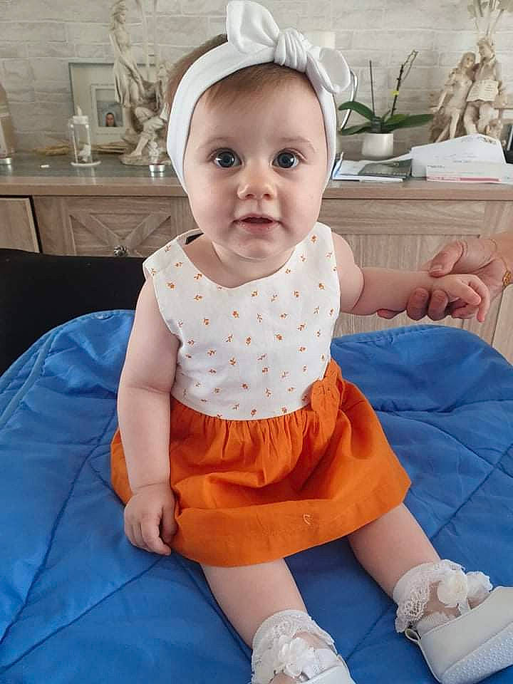 Yuna participe au concours pour gagner de l'argent avec cette photo : baby, baby_toddler_clothing, child, dress, electric_blue, eye, fun, happy, houseplant, knee, pattern, person, pink, sitting, skin, sleeve, sock, standing, t_shirt, toddler