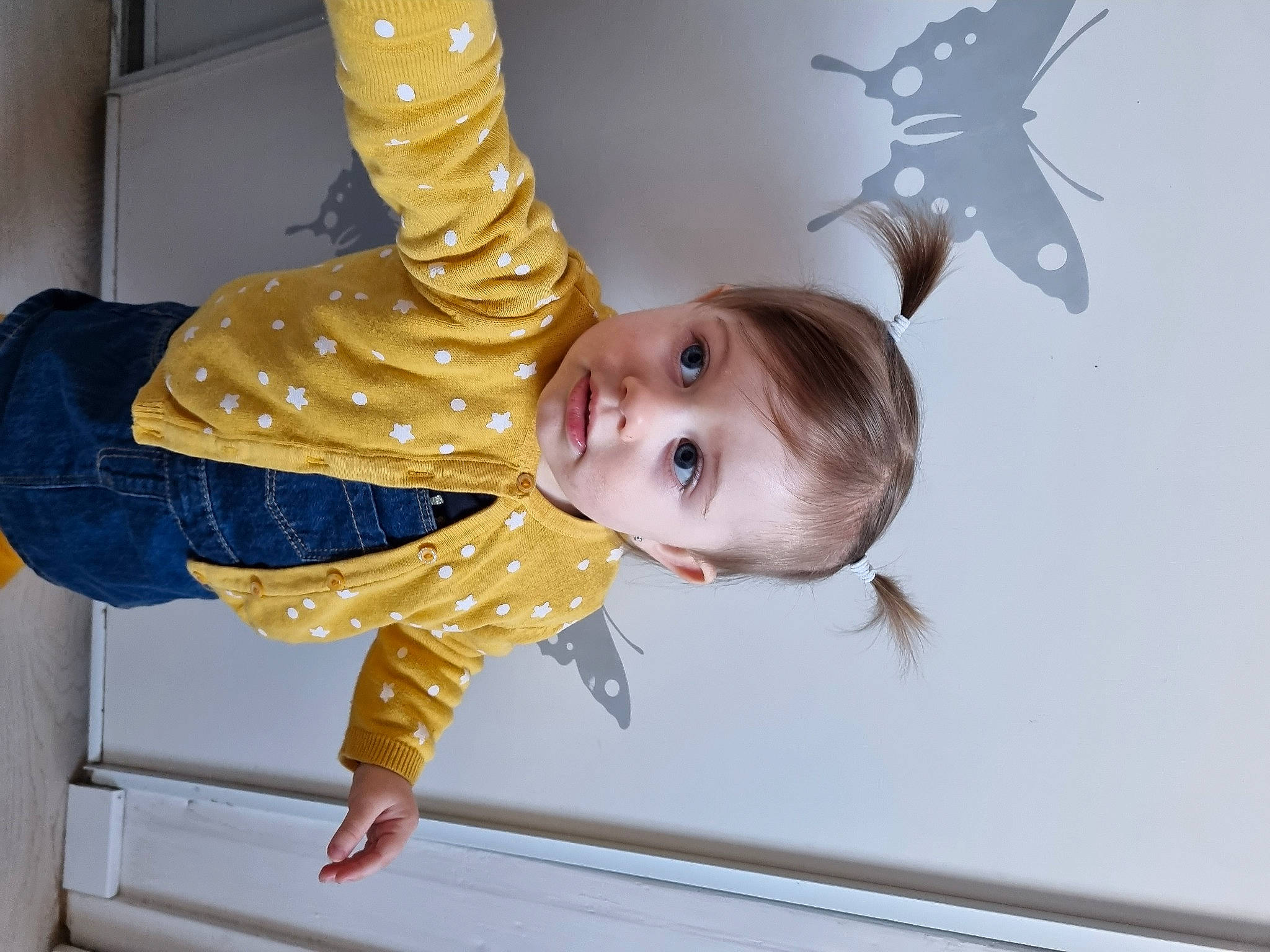 Yuna participe au concours pour gagner de l'argent avec cette photo : baby, baby_toddler_clothing, cheek, child, fashion_accessory, finger, fun, gesture, happy, pattern, person, room, sitting, sleeve, thumb, toddler, wood