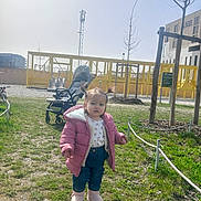 Sandra a rejoint le concours — aidez-le/la à gagner de superbes lots ! child, toddler, pigtails, pink_jacket, pink_boots, jeans, stroller, playground, slide, grass, park, rope_fence, tree, building, sunny_day, shadow, face, walking, winter_coat, outdoor_fun