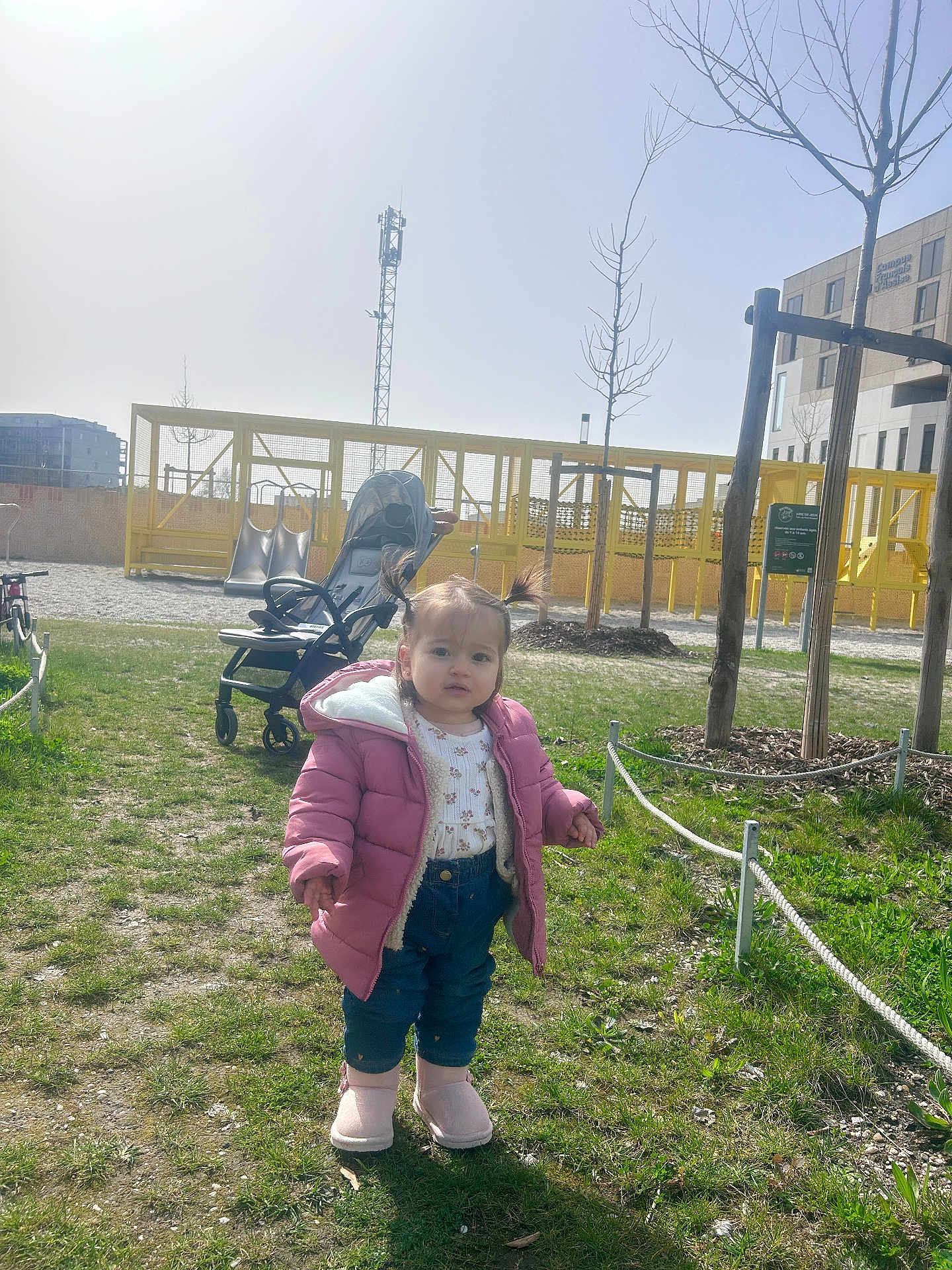 Sandra a rejoint le concours — aidez-le/la à gagner de superbes lots ! child, toddler, pigtails, pink_jacket, pink_boots, jeans, stroller, playground, slide, grass, park, rope_fence, tree, building, sunny_day, shadow, face, walking, winter_coat, outdoor_fun