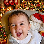 Timéo participe au concours pour gagner de l'argent avec cette photo : baby, bib, celebration, child, christmas_tree, cozy, decorations, face, festive, fireplace, gift, happy, holiday, indoor, infant, santa_hat, seat, smiling, stockings, warmth