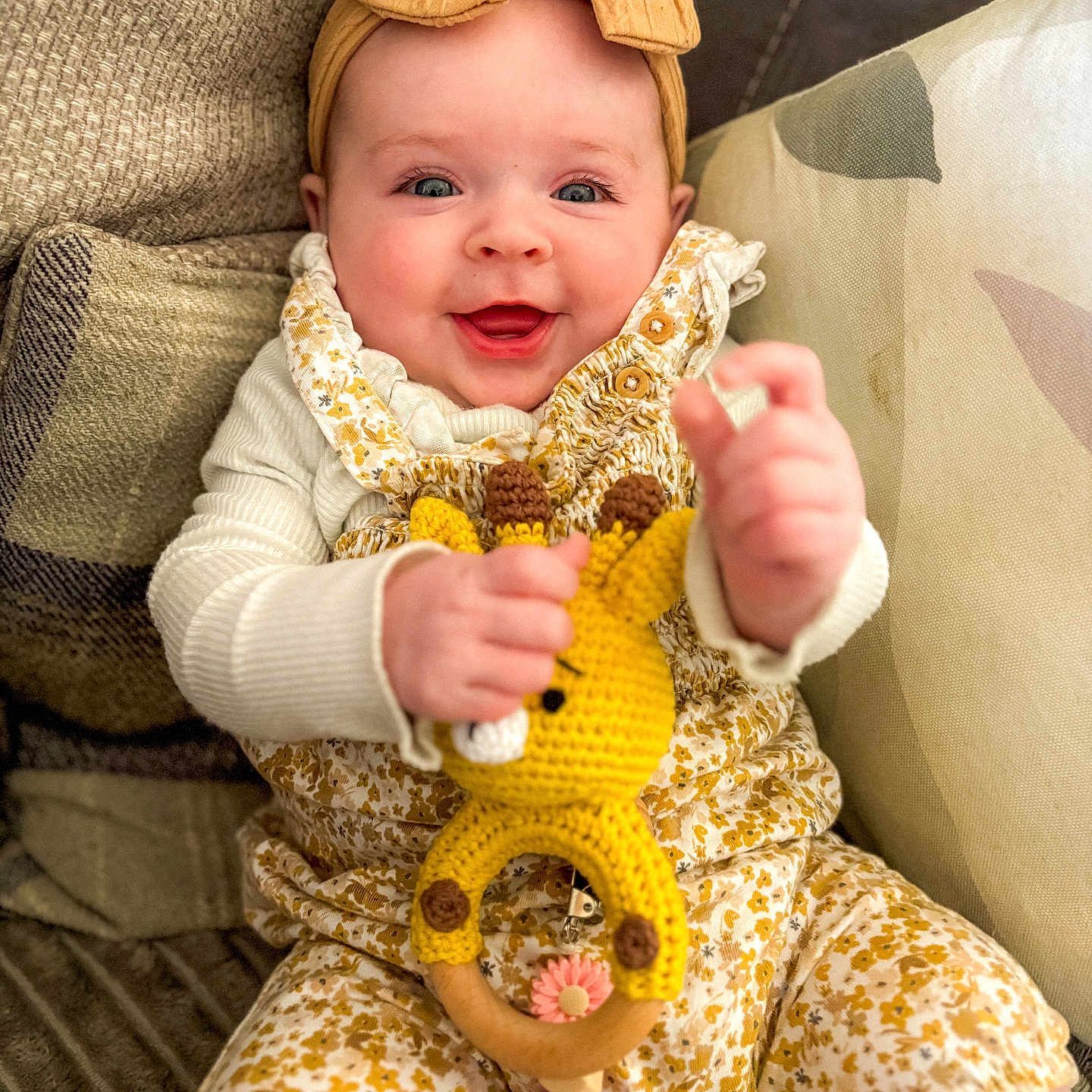 Myla-Rose is registered to the contest to win money with this photo: baby, bow, child, clothing, couch, crocheted, cute, face, floral, giraffe, hand, happy, headband, indoor, infant, overalls, pillow, sitting, smiling, toy