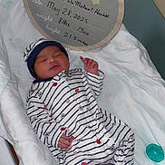 Adonis joined the competition — help win amazing prizes! newborn, baby, infant, sleeping, onesie, hat, blanket, bassinet, hospital, sign, birth_announcement, wooden_sign, striped_clothing, sports_pattern, pacifier, footed_pajamas, cute, peaceful, indoors, portrait