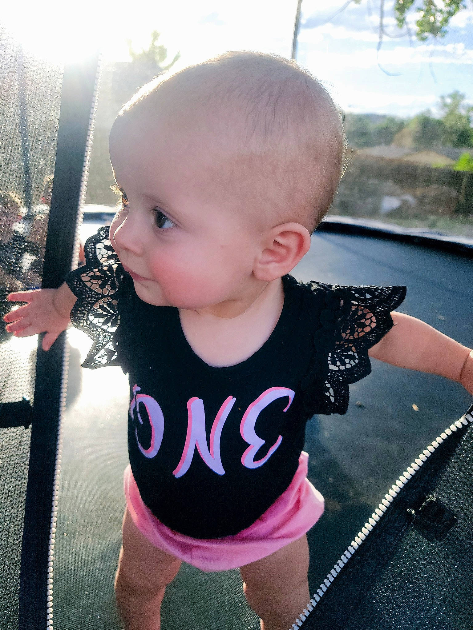 Emma is registered to the contest to win money with this photo: baby, baby_toddler_clothing, black, cheek, facial_expression, finger, hairstyle, hand, happy, iris, joint, lip, neck, person, pink, product, shoulder, skin, sleeve, standing