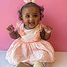 baby, bow, child, clothing, curly_hair, cute, face, fashion, girl, hands, happy, indoor, infant, pink_background, pink_dress, portrait, shoes, sitting, smiling, toddler
