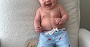 Coast joined the competition — help win amazing prizes! baby, background_wall, bare_chest, blue_shorts, child, cute, feet, fluffy_chair, four_months, hair_tuft, hands, happy, indoor, infant, lobster_pattern, portrait, sitting, skin, smiling, wooden_sign