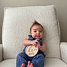 baby, infant, three_months, blue_clothing, armchair, white_fabric, sign, wooden_sign, mohawk_hairstyle, cute, portrait, sitting, bare_feet, indoor, child, young_baby, smiling, hands, feet, person