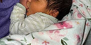 Ravi is registered to the contest to win money with this photo: baby, blanket, sleeping, newborn, person, hand, nail_polish, clothing, floral_pattern, soft_texture, closeup, indoor, comfort, peaceful, skin, face, hair, caring, toddler, rest