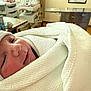 Ravi is registered to the contest to win money with this photo: newborn, baby, hospital, blanket, hat, sleeping, infant, swaddled, medical_equipment, bedside_table, room, indoors, person, closeup, face, cozy, resting, healthcare, soft_light, comfort