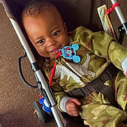 Blaze joined the competition — help win amazing prizes! baby, smiling, child, stroller, camouflage_clothing, dinosaur_design, pacifier, mickey_mouse, indoor, carpet, seatbelt, happy, cute, infant, playful, young_child, clothing, toy, person, relaxing
