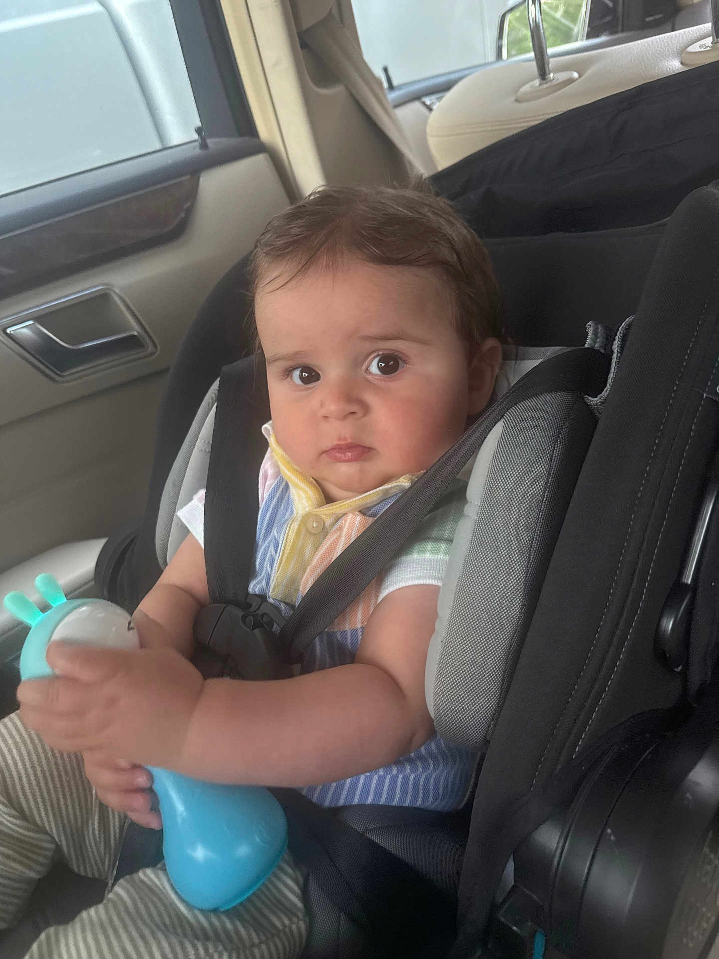 Liam joined the competition — help win amazing prizes! baby, child, car_seat, toy, car_interior, seatbelt, infant, person, holding, clothing, striped_pants, colorful_shirt, safety, seat, cute, closeup, indoor, baby_toy, young_child, car_window
