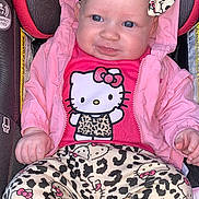 Naiari is registered to the contest to win money with this photo: baby, child, car_seat, pink_jacket, headband, hello_kitty, leopard_print, clothing, infant, cute, portrait, smiling, sitting, indoors, person, baby_clothes, accessory, fashion, young_child, apparel