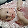 baby, infant, pink_dress, ruffled_blanket, closeup, face, hand, soft_texture, cute, newborn, skin, portrait, lying_down, adorable, child, small_fingers, expression, resting, indoors, fabric