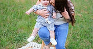 Ryker joined the competition — help win amazing prizes! child, woman, outdoor, grass, stool, basket, flowers, blanket, jeans, sandals, affection, kiss, smile, casual_clothing, nature, greenery, portrait, family, happy, playful