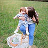 child, woman, outdoor, grass, stool, basket, flowers, blanket, jeans, sandals, affection, kiss, smile, casual_clothing, nature, greenery, portrait, family, happy, playful