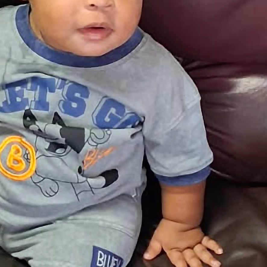 Khylon joined the competition — help win amazing prizes! child, toddler, baby, portrait, sitting, couch, leather_couch, braids, beads, gray_clothing, cartoon_shirt, shorts, shoe, curious, expression, indoor, home, closeup, person, photography