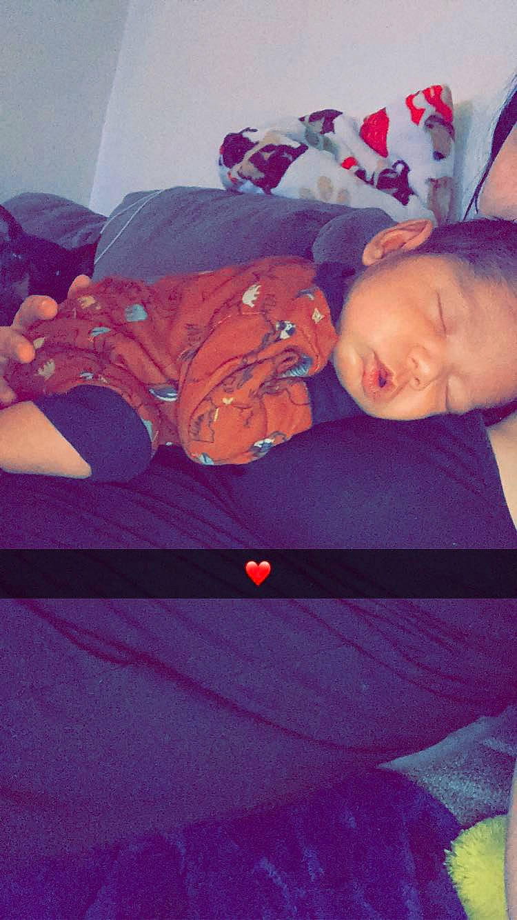 Elvie is registered to the contest to win money with this photo: baby, baby_toddler_clothing, cheek, comfort, couch, fun, happy, linens, magenta, mouth, orange, person, pink, purple, red, room, sitting, tints_and_shades, toddler, tree