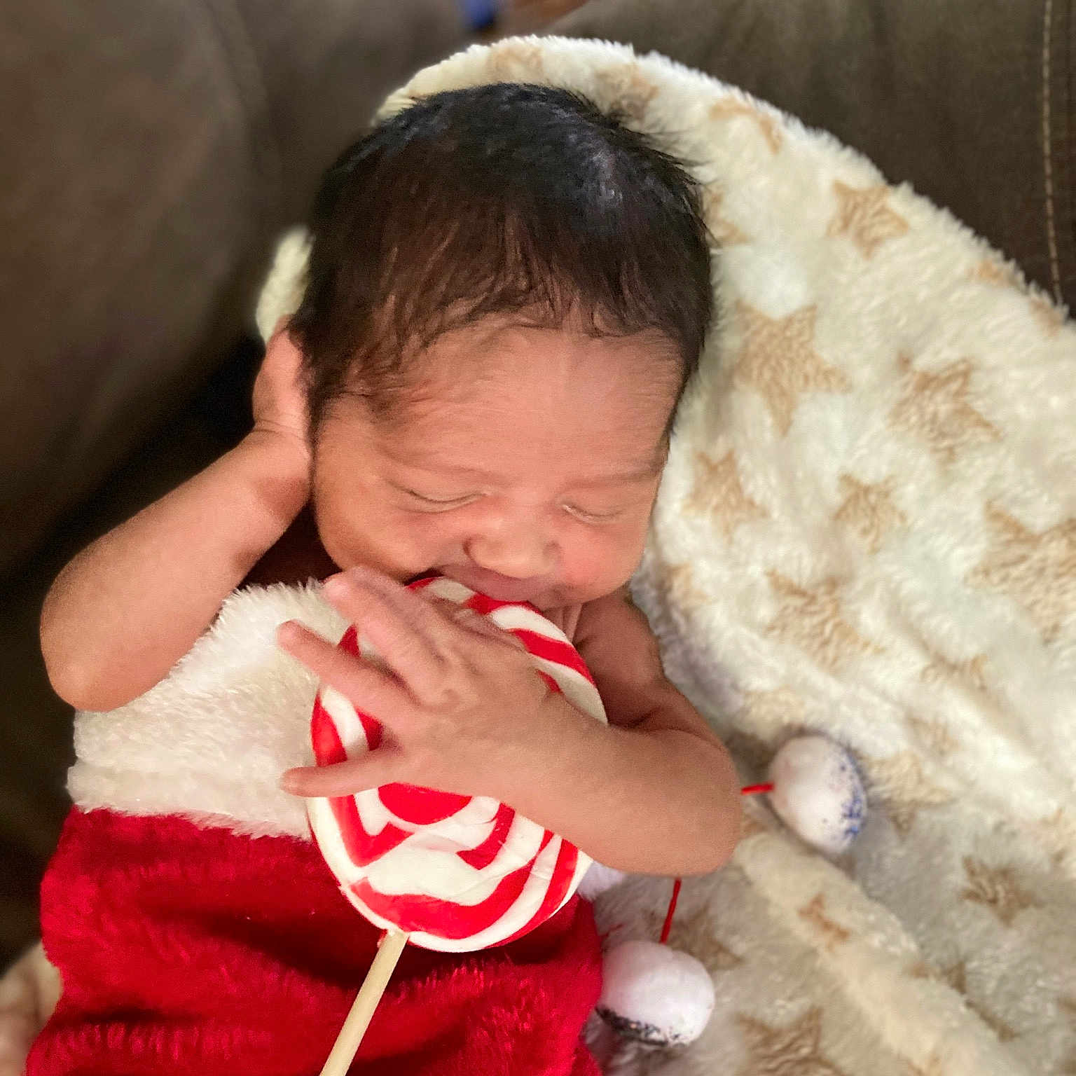 Elvie is registered to the contest to win money with this photo: baby, baby_toddler_clothing, cheek, child, christmas, comfort, couch, event, eye, finger, fur, gesture, hand, happy, head, holiday, nose, sitting, toddler, tree