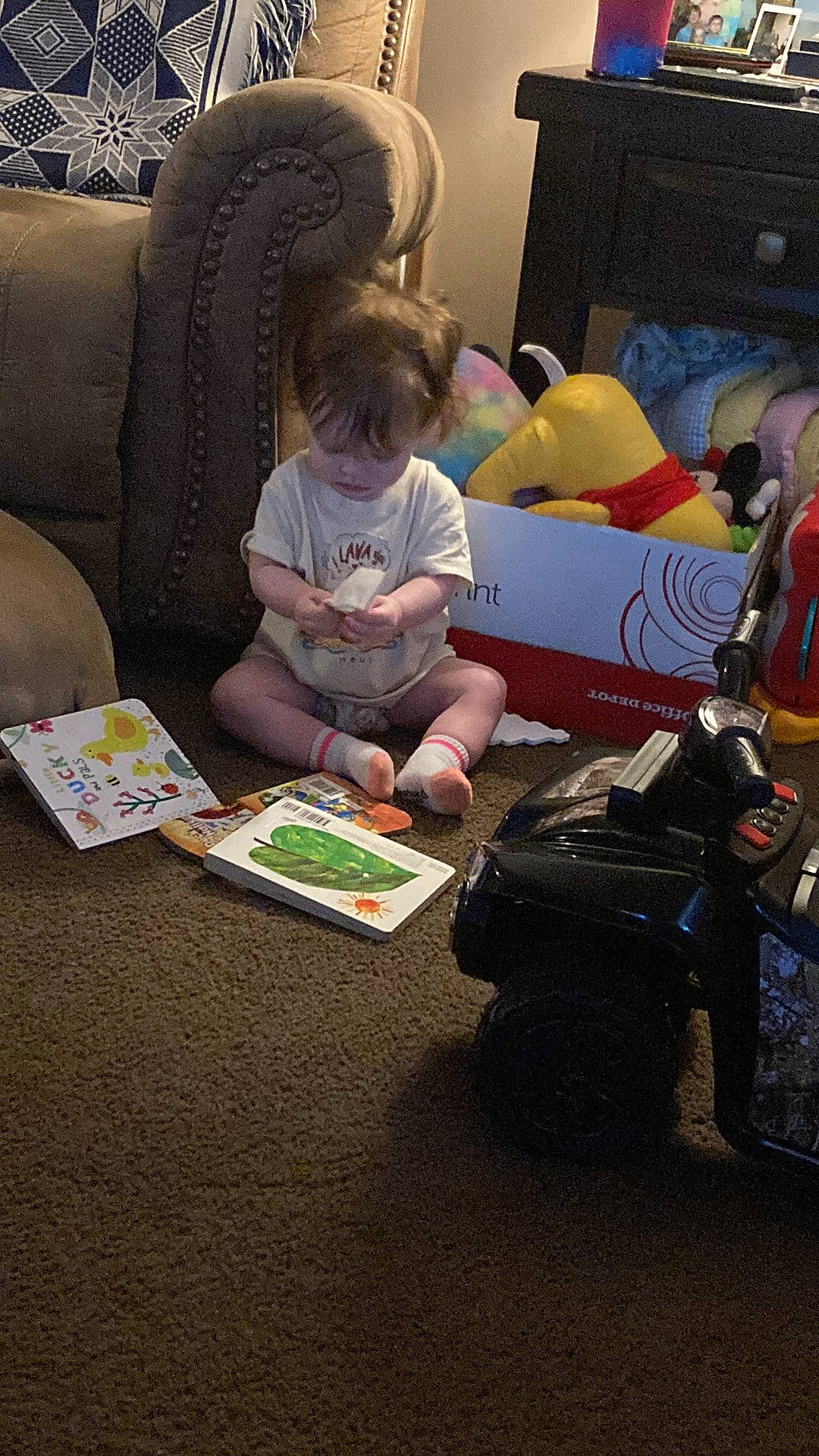 Marie is registered to the contest to win money with this photo: baby, child, comfort, couch, flooring, fun, gadget, games, lap, living_room, luggage_and_bags, person, play, reading, room, sharing, sitting, tire, toddler, toy