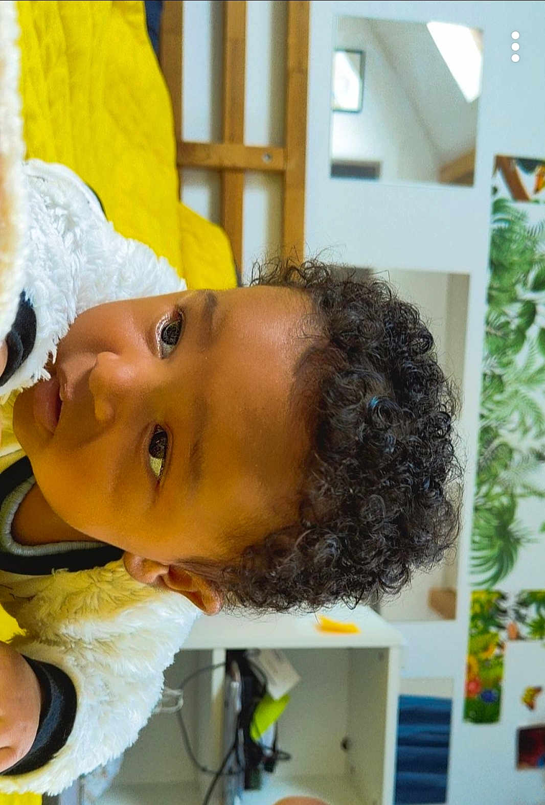 Lowen participe au concours pour gagner de l'argent avec cette photo : child, curly_hair, face, indoor, yellow_blanket, white_jacket, cozy, portrait, young_child, curious, furniture, wall_art, greenery, modern_room, close_up, skin, expression, head, person, casual