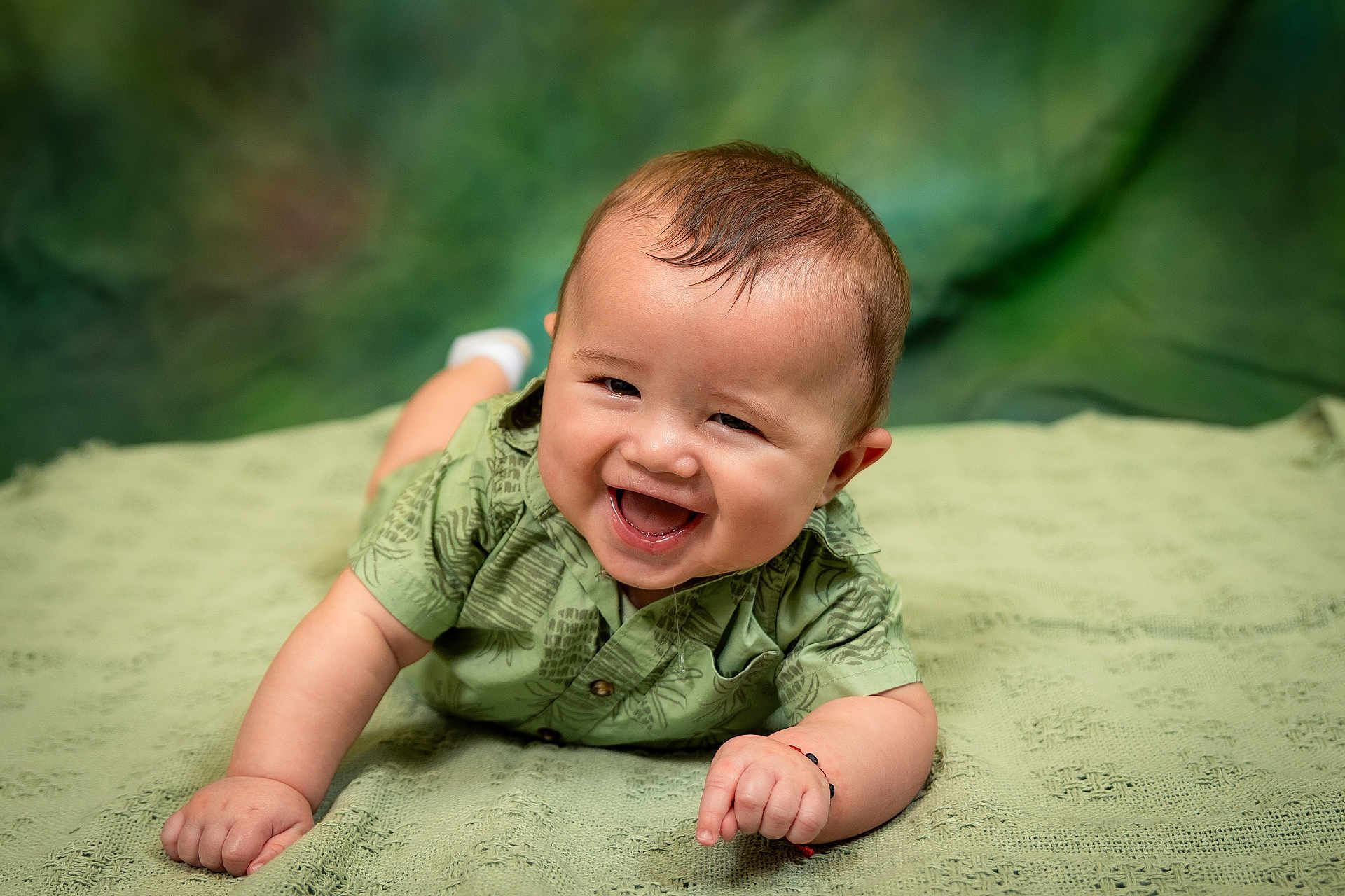 Fabián joined the competition — help win amazing prizes! baby, smiling, green_shirt, lying_down, blanket, happy, cute, infant, portrait, face, child, toddler, skin, hair, indoors, crawling, expression, small_hands, closeup, eyes