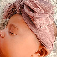 Ivory is registered to the contest to win money with this photo: accessories, baby, bandana, bonnet, clothing, face, hat, head, headband, knot, person, photography, portrait, skin, sleeping, towel, turban