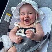 Tatum is registered to the contest to win money with this photo: baby, smiling, hat, crochet_top, baby_seat, plush_toy, happy, chubby_cheeks, infant, clothing, face, cute, child, indoors, seat, white_hat, soft_toy, relaxing, portrait, hands
