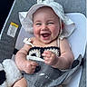 baby, smiling, hat, crochet_top, baby_seat, plush_toy, happy, chubby_cheeks, infant, clothing, face, cute, child, indoors, seat, white_hat, soft_toy, relaxing, portrait, hands
