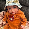 Noah a rejoint le concours — aidez-le/la à gagner de superbes lots ! baby, child, hat, bucket_hat, orange_clothing, bear_patch, couch, knitted_blanket, texture, cute, portrait, indoor, infant, smiling, cozy, seated, young_child, clothing, face, person