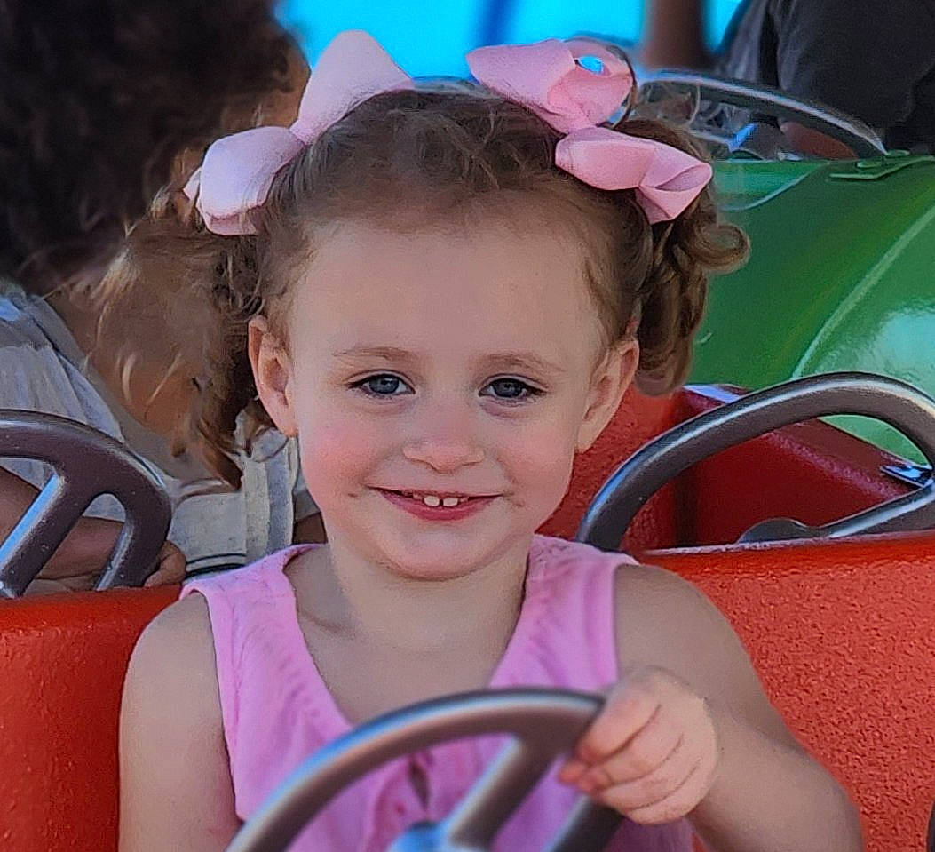 Alayna is registered to the contest to win money with this photo: baby_toddler_clothing, chair, child, cool, eyelash, fashion_accessory, fun, happy, headband, headpiece, iris, joy, leisure, magenta, person, pink, skin, smile, snapshot, steering_wheel