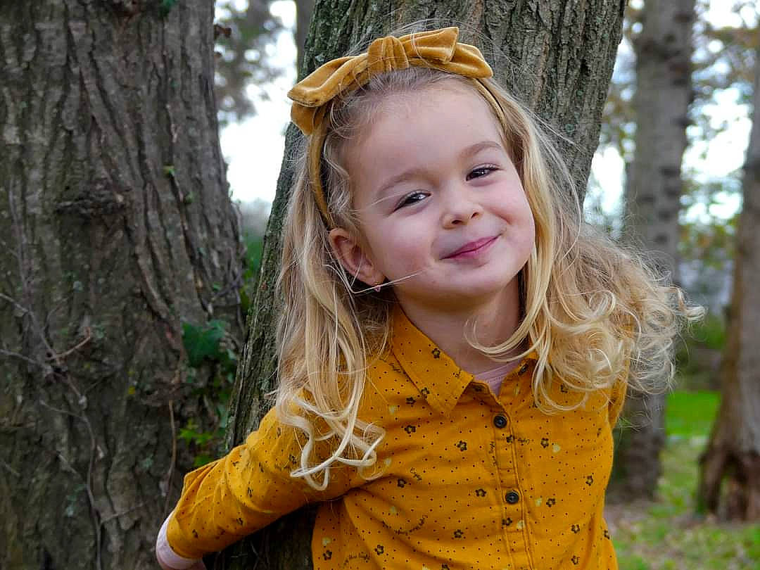 Clara participe au concours pour gagner de l'argent avec cette photo : branch, eye, face, flash_photography, grass, happy, head, iris, joy, leaf, lip, nature, outerwear, people_in_nature, person, plant, skin, smile, standing, sunlight