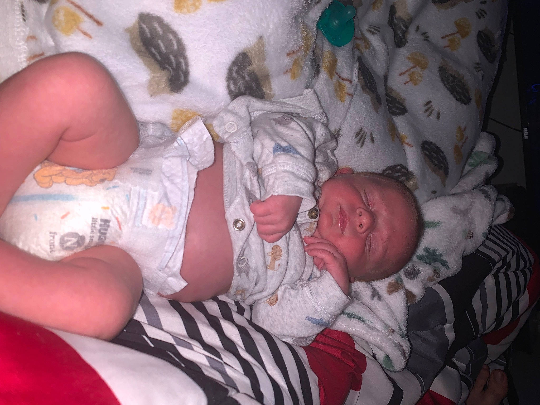 Kooper is registered to the contest to win money with this photo: arm, baby, baby_toddler_clothing, chest, comfort, elbow, finger, hand, human_body, human_leg, knee, leg, linens, mouth, pattern, people, person, skin, thigh, toddler