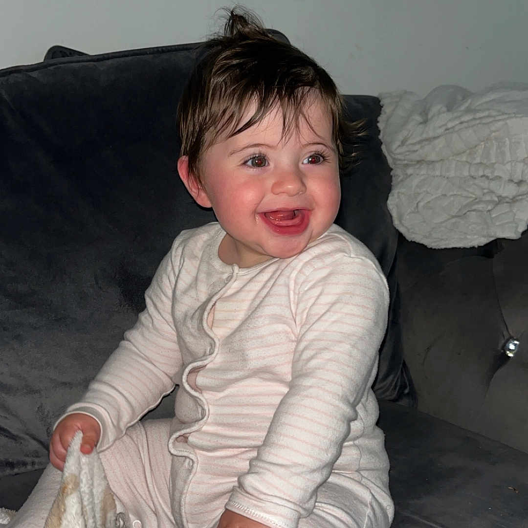 Viyan-Rose joined the competition — help win amazing prizes! baby, blanket, bodypart, clothing, couch, cushion, face, finger, furniture, hand, happy, head, homedecor, indoors, pants, person, photography, portrait, sitting, smile