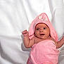 baby, infant, pink_towel, hooded_towel, wrapped, raising_fist, curious, blue_eyes, skin, blanket, soft, white_background, cute, newborn, child, portrait, indoors, expression, small_hands, towel