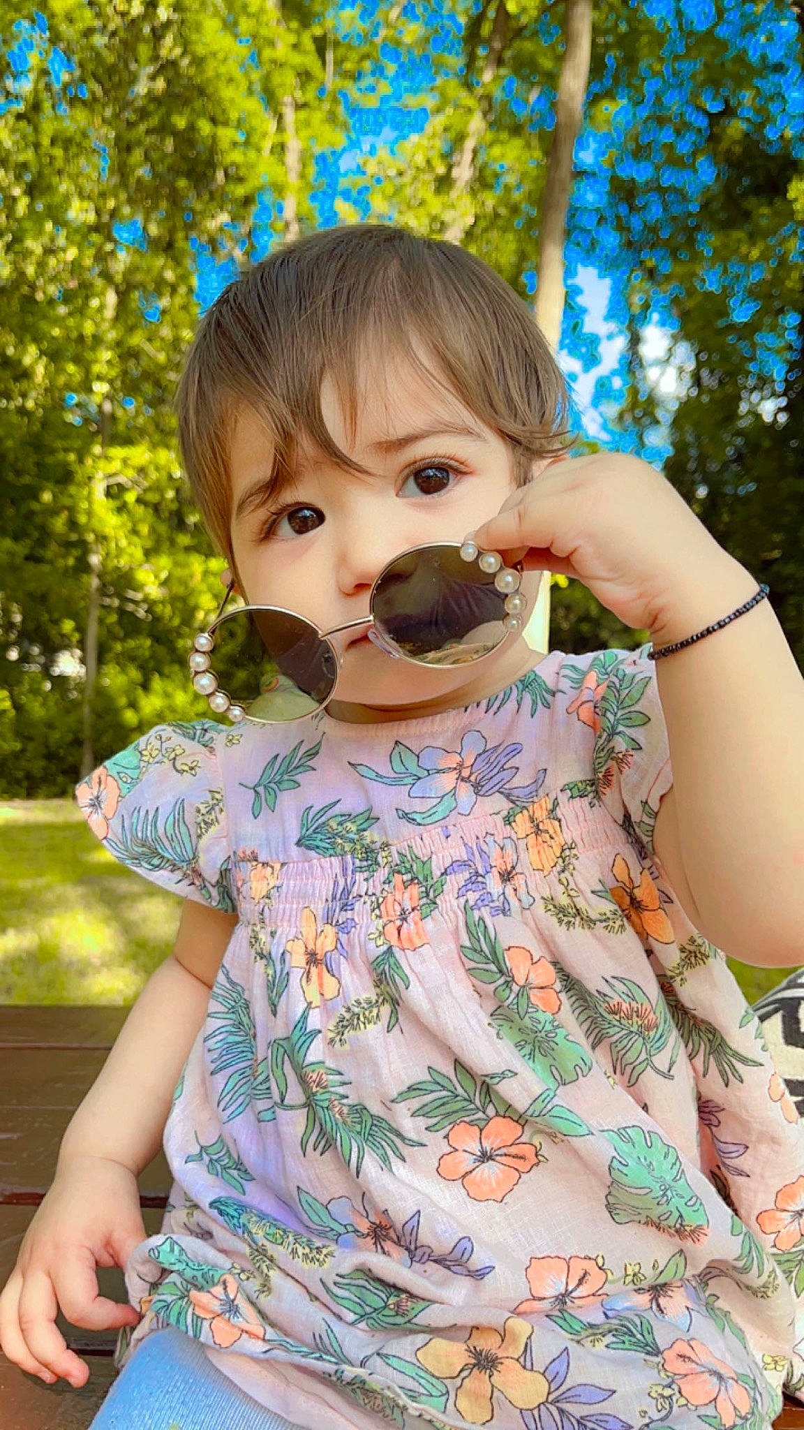 Ariya is registered to the contest to win money with this photo: baby_toddler_clothing, botany, child, dress, eyelash, finger, fun, grass, hand, happy, lip, pattern, people_in_nature, person, pink, plant, skin, sleeve, summer, toddler