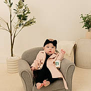 Mallory joined the competition — help win amazing prizes! baby, child, armchair, trench_coat, headband, starbucks_cup, indoor, plant, pottery, minimalist, cozy, carpet, footwearless, cute, portrait, furniture, expression, fashion, relaxing, neutral_colors
