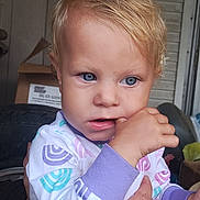 Catherine joined the competition — help win amazing prizes! baby, child, toddler, portrait, face, blue_eyes, blond_hair, serious_expression, finger_nibbling, close_up, colorful_clothing, pajamas, indoors, window, adult_hand, supported_child, sitting, photography, home, natural_light