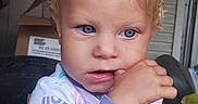 Catherine joined the competition — help win amazing prizes! adult_hand, baby, blond_hair, blue_eyes, child, close_up, colorful_clothing, face, finger_nibbling, home, indoors, natural_light, pajamas, photography, portrait, serious_expression, sitting, supported_child, toddler, window