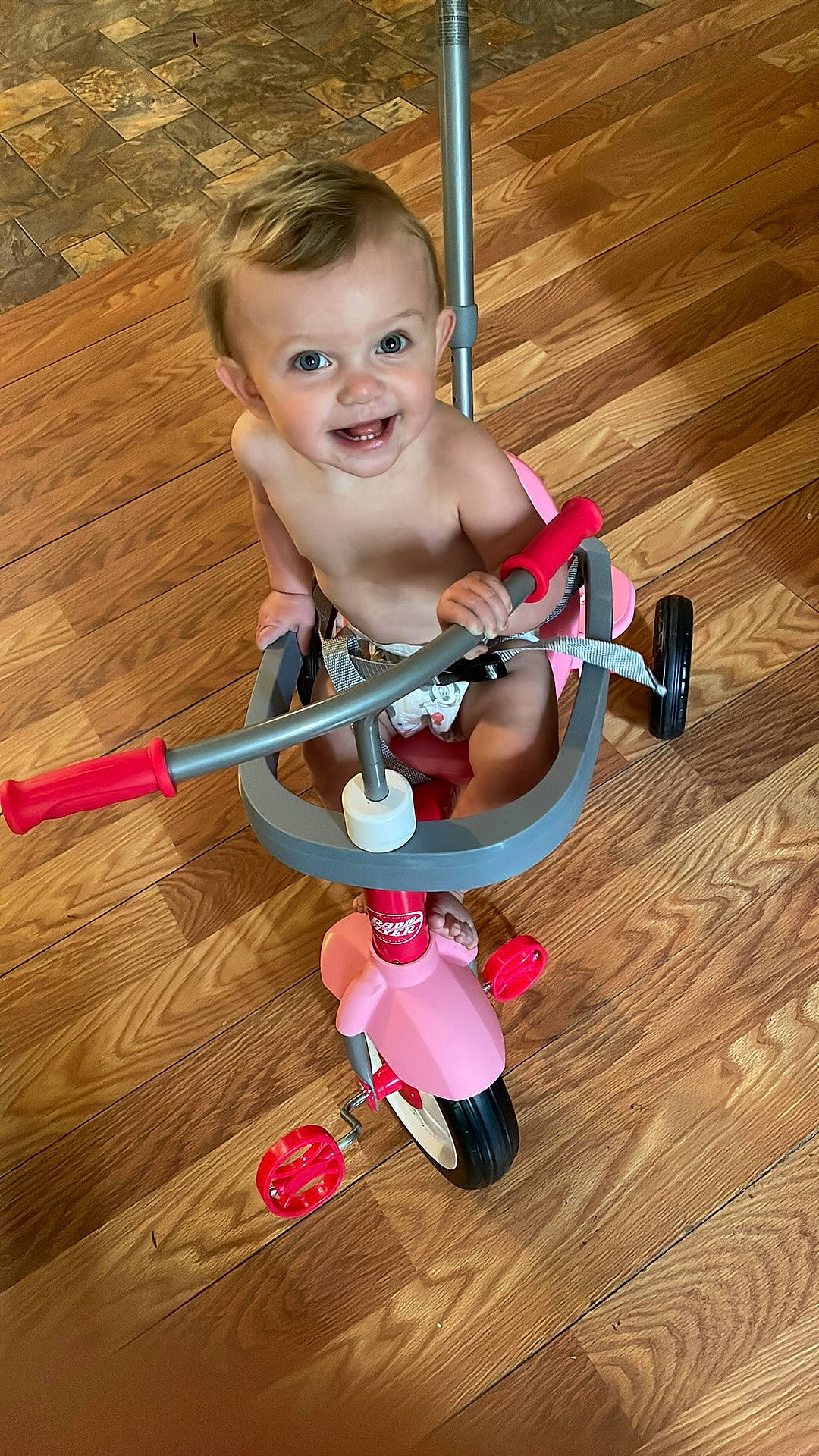 Alaina is registered to the contest to win money with this photo: baby, baby_products, baby_toddler_clothing, baby_toys, child, face, floor, flooring, fun, happy, hardwood, head, person, smile, tire, toddler, toy, varnish, wheel, wood