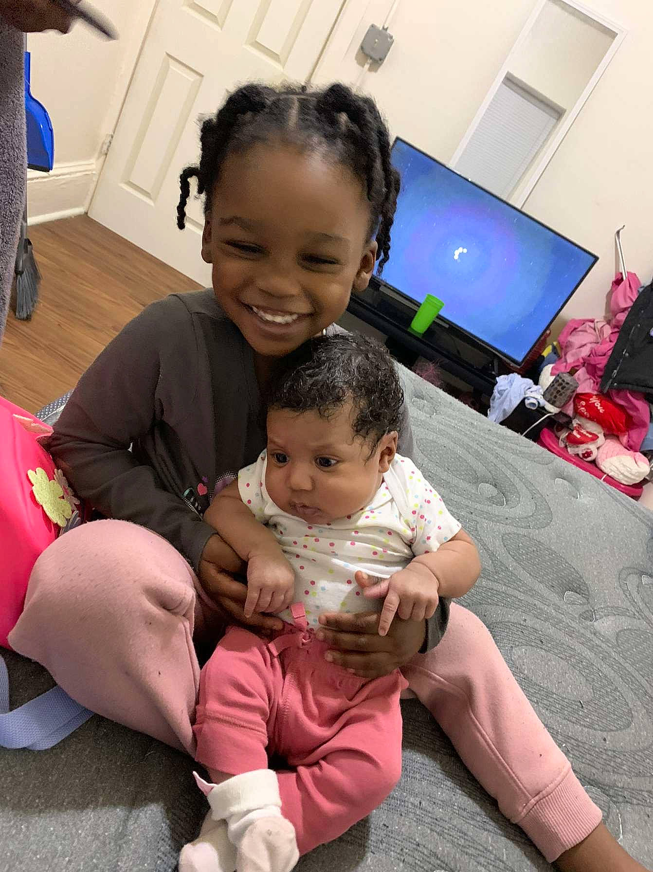 Laylah is registered to the contest to win money with this photo: baby, baby_toddler_clothing, child, event, facial_expression, fun, happy, head, human_leg, interaction, joy, lap, leisure, person, pink, skin, smile, standing, t_shirt, thigh