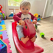 Gabriel a rejoint le concours — aidez-le/la à gagner de superbes lots ! toddler, child, indoor, rocking_horse, toy, playroom, floor, colorful, foot, barefoot, plastic_toy, window, light, happy, smiling, clothing, jeans, shirt, person, young_child