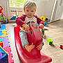 toddler, child, indoor, rocking_horse, toy, playroom, floor, colorful, foot, barefoot, plastic_toy, window, light, happy, smiling, clothing, jeans, shirt, person, young_child