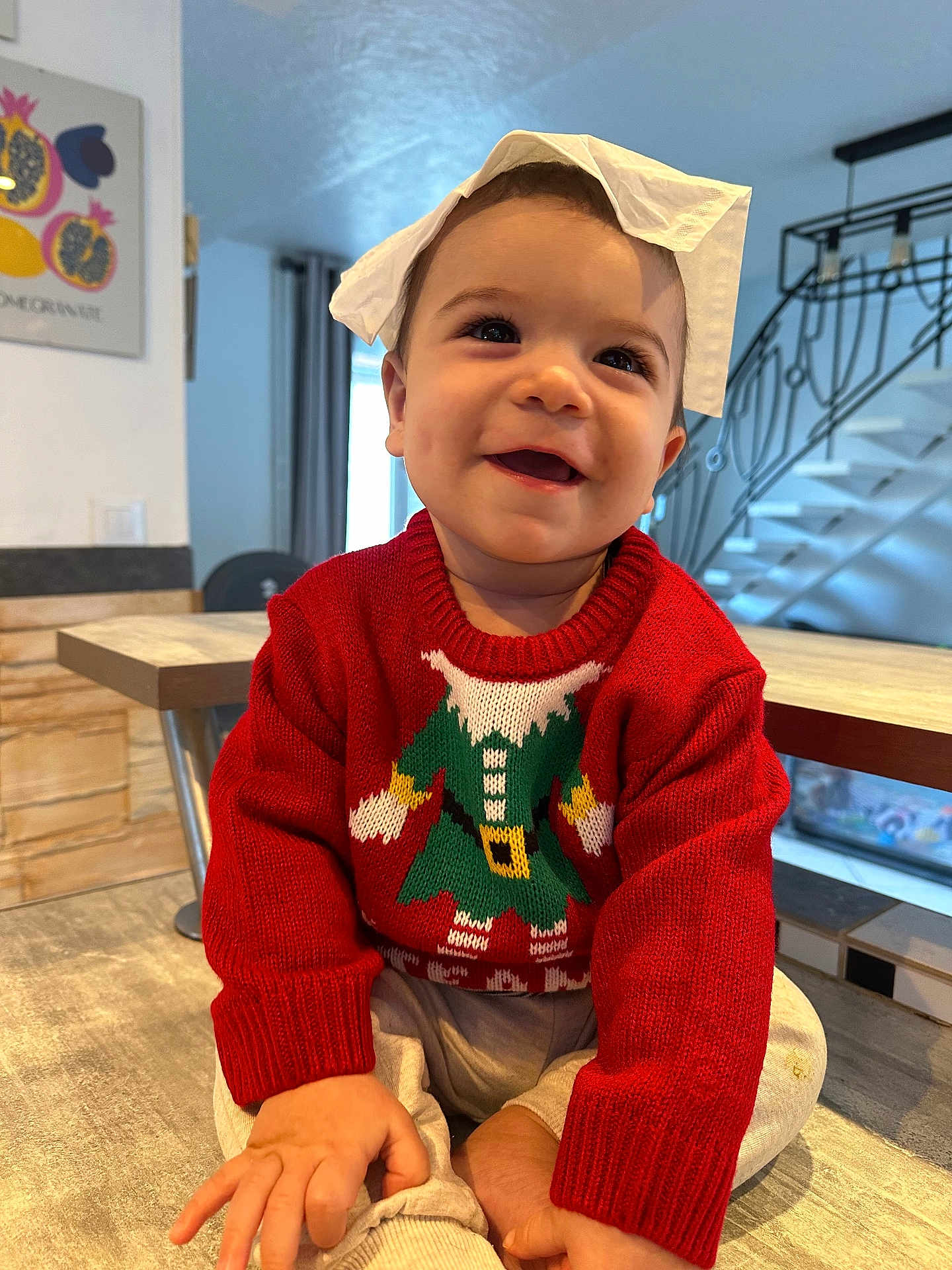 Liam a rejoint le concours — aidez-le/la à gagner de superbes lots ! baby, child, smiling, red_sweater, elf_design, tissue_paper, indoor, wooden_table, happy, cute, portrait, sitting, home, cozy, playful, face, person, hand, clothing, infant