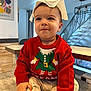 toddler, child, baby, red_sweater, elf_design, napkin, indoor, table, modern_decor, staircase, smiling, cute, casual_pose, long_sleeves, cozy, playful, person, clothing, face, headwear