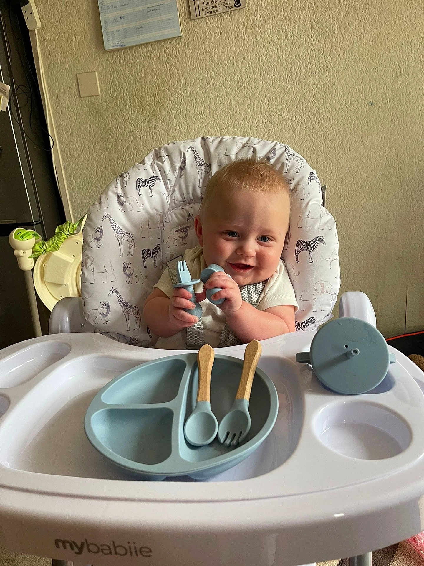 Kayson joined the competition — help win amazing prizes! baby, high_chair, baby_utensils, fork, spoon, sippy_cup, feeding, smile, child, infant, cute, happy, kitchen, plate, seat, animal_print, giraffe, zebra, wall, indoor