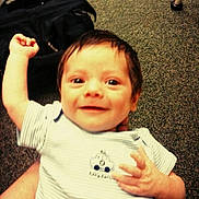 Seger is registered to the contest to win money with this photo: baby, child, smiling, arm_raised, striped_shirt, car_cartoon, indoor, carpet, hand, face, person, cute, happy, young_child, infant, casual, clothing, portrait, expression, background